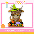 A wooden paint kit featuring a cartoon cow wearing a witch's hat, surrounded by Halloween-themed decorations such as candy and pumpkins.