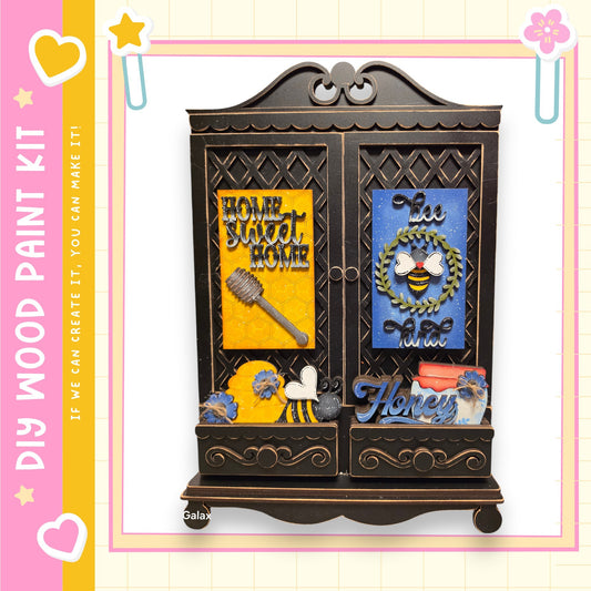 The image is a wooden paint kit featuring a decorative cabinet with various items and text.