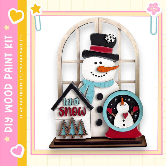 A wooden snowman and a snow globe are displayed in the image, with a pink and yellow border.