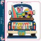 A colorful and whimsical illustration of a truck bed, decorated with various beach-themed items such as a surfboard, flip flops, sunglasses, and a beach ball. The text "BEACH LIFE" is prominently displayed on the truck bed, and the phrase "Here comes the SUN" is written on a sign attached to the truck.
