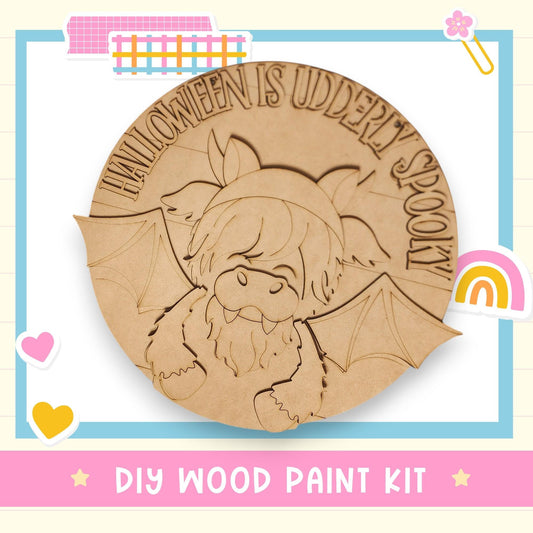 a DIY wood paint kit for a Halloween-themed project, with a wooden bat and the text "HALLOWEEN IS UDDERY SPOKY" carved into it.