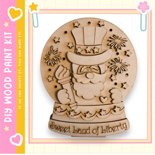 A wooden snow globe with a smiling Santa Claus figure and stars, along with the text "Sweet land of liberty" on the base.