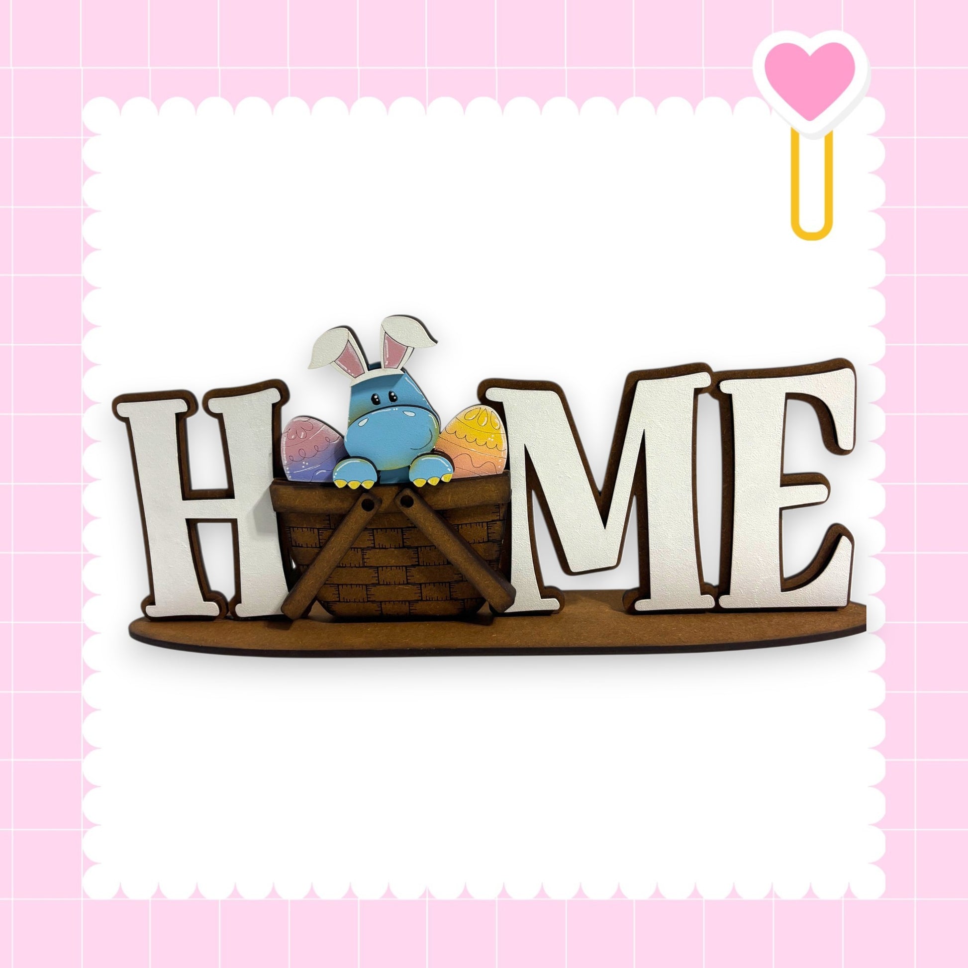 A wooden sign with the word "HOME" in large letters, featuring a small blue bunny sitting in a basket.