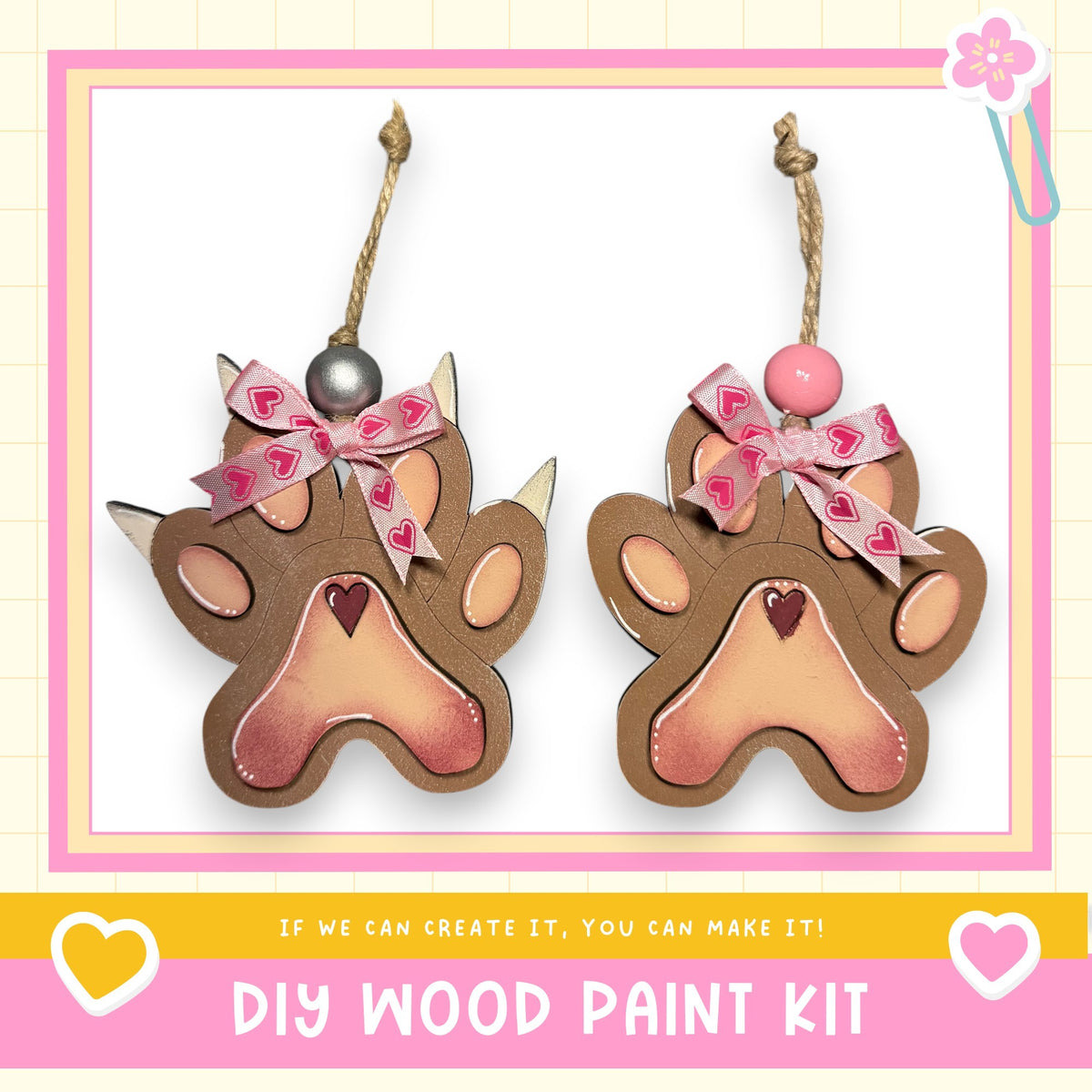 two wooden paw-shaped ornaments with heart-shaped beads on top, hanging from strings. The text below the image reads "DIY WOOD PAINT KIT" and "If we can create it, you can make it!"