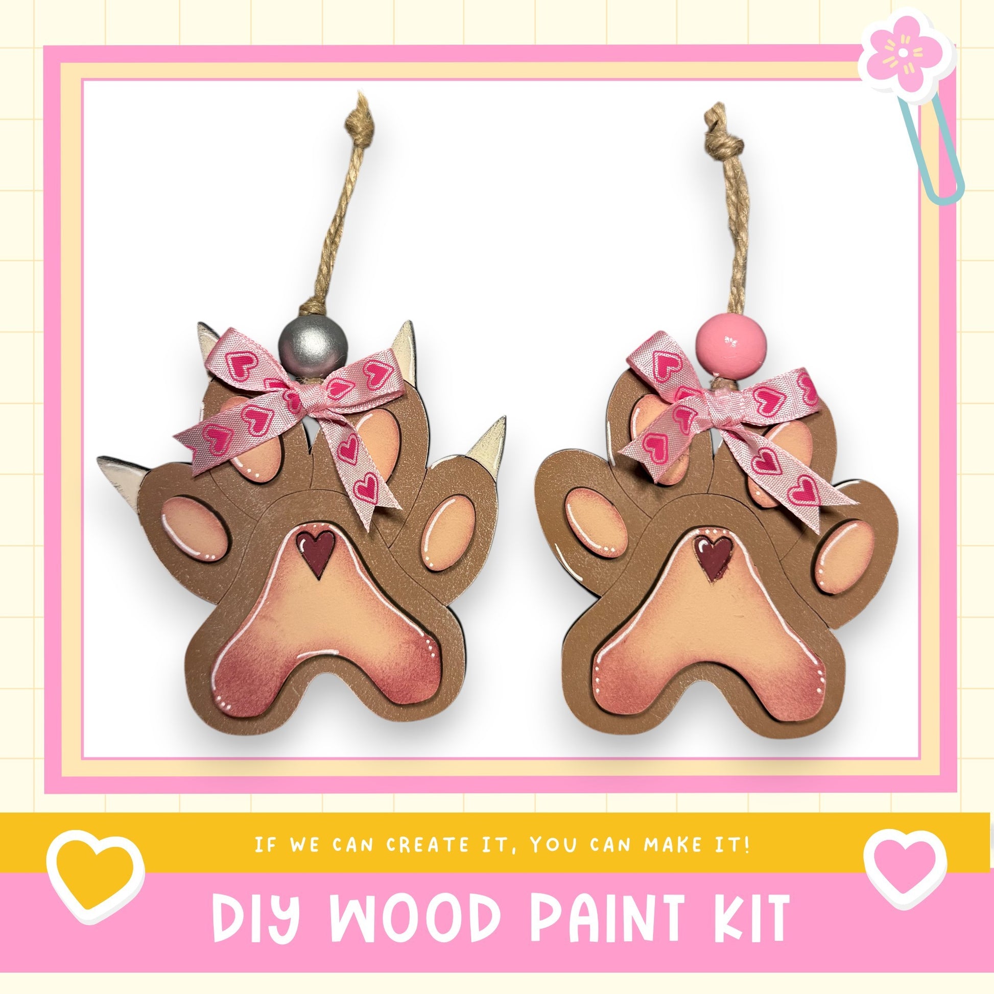 two wooden paw-shaped ornaments with heart-shaped beads on top, hanging from strings. The text below the image reads "DIY WOOD PAINT KIT" and "If we can create it, you can make it!"