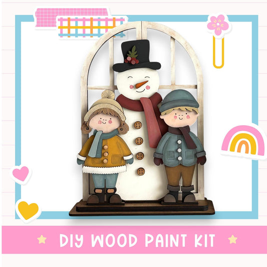 A DIY wood paint kit featuring a snowman, two children, and a heart, with the text "DIY WOOD PAINT KIT" at the bottom.