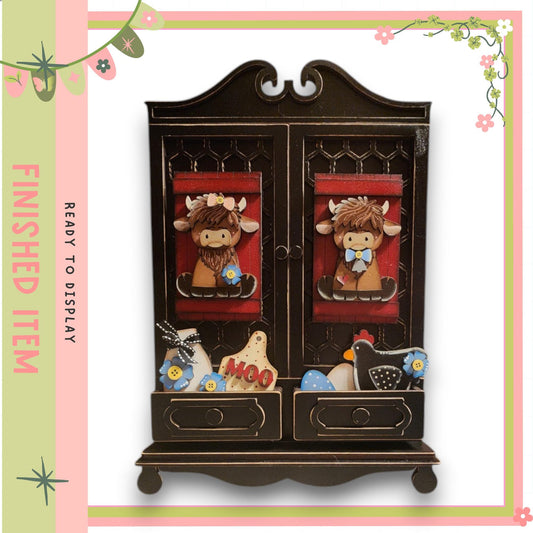 A wooden cabinet with two drawers, each containing various small animal figurines, such as cows and chickens. The cabinet has a decorative design with floral patterns around the edges.