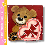 A wooden teddy bear holding a heart-shaped object with a red ribbon, set against a red background with white hearts scattered throughout.