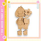 A wooden cutout of a cartoon duck holding a flower is displayed against a pink and yellow background.