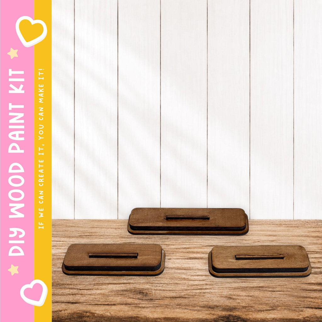 three wooden blocks or stands placed on a wooden surface, with a pink and yellow striped border on the left side.