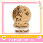 a DIY wood paint kit for creating a wooden snow globe. The kit includes a snow globe with a deer and snowflakes, along with instructions for creating the snow globe.