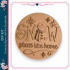 A wooden sign with the text "SNOW place like home" carved into it, featuring a snowman and snowflakes.