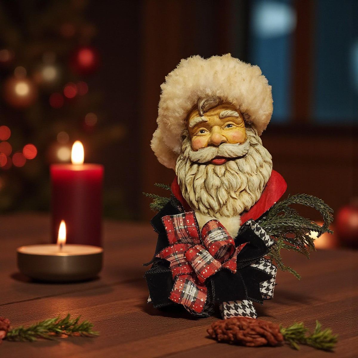A Christmas-themed scene featuring a carved Santa Claus figurine, a lit red candle, and some pine branches on a wooden surface.