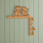 A wooden shelf with two wooden figures, likely representing a couple, and various wooden objects such as a Christmas tree, a candy cane, and a cookie.