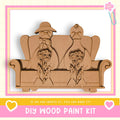 A DIY wood paint kit featuring a wooden sculpture of a man and a woman sitting on a couch, holding flowers.