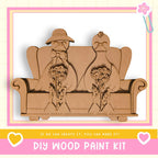 A DIY wood paint kit featuring a wooden sculpture of a man and a woman sitting on a couch, holding flowers.