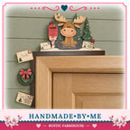 A wooden shelf with a moose figurine and various holiday decorations, including a wreath, a Christmas tree, and a "Santa's" card. The shelf is mounted on a wooden frame, and there are several holiday-themed cards attached to it. The image also includes text that reads "HANDMADE BY ME" and "RUSTIC FARMHOUSE".