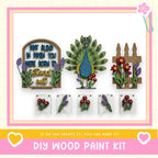 The image is a DIY wood paint kit featuring various wooden elements, including a peacock, flowers, and a wooden fence. The kit appears to be made of wood and is designed for painting and decorating wooden surfaces.