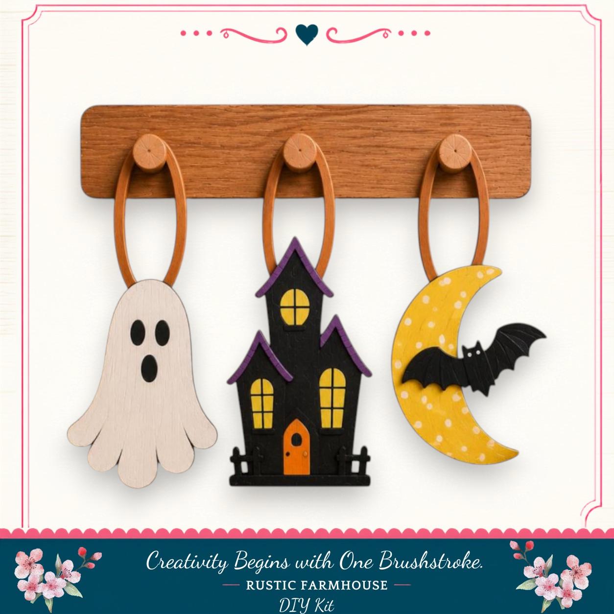 a Halloween-themed DIY kit, including a ghost, a house, and a bat, all hanging from a wooden board.