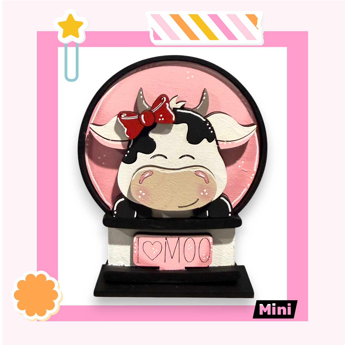 A pink and white cow figurine with a bow on its head, sitting on a pink base with the word "Moo" written on it.