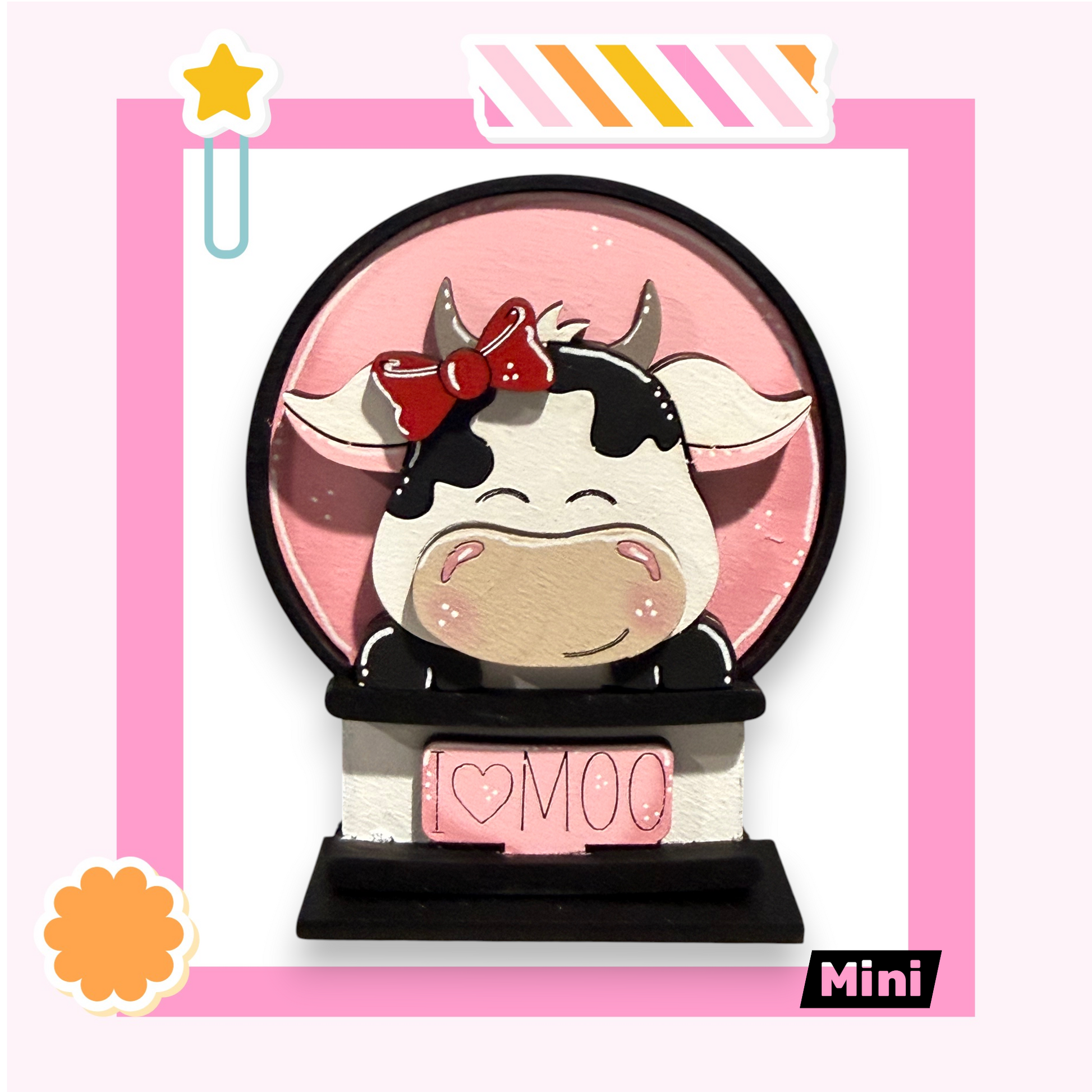 A pink and white cow figurine with a bow on its head, sitting on a pink base with the word "Moo" written on it.