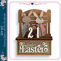 A wooden sign with the number "21" and the text "DAYS UNTIL EASTER" on it, along with two cartoon rabbit figures dressed in formal attire.