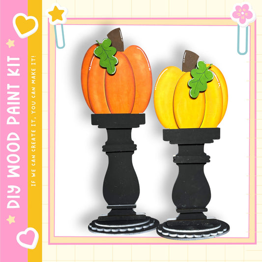 two wooden pumpkin ornaments, each with a green leaf and a brown stem, placed on black pedestals.