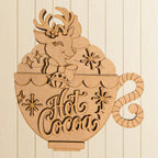 A wooden cutout of a cup with a reindeer and snowflakes, along with the text "Hot Cocoa" written on it.