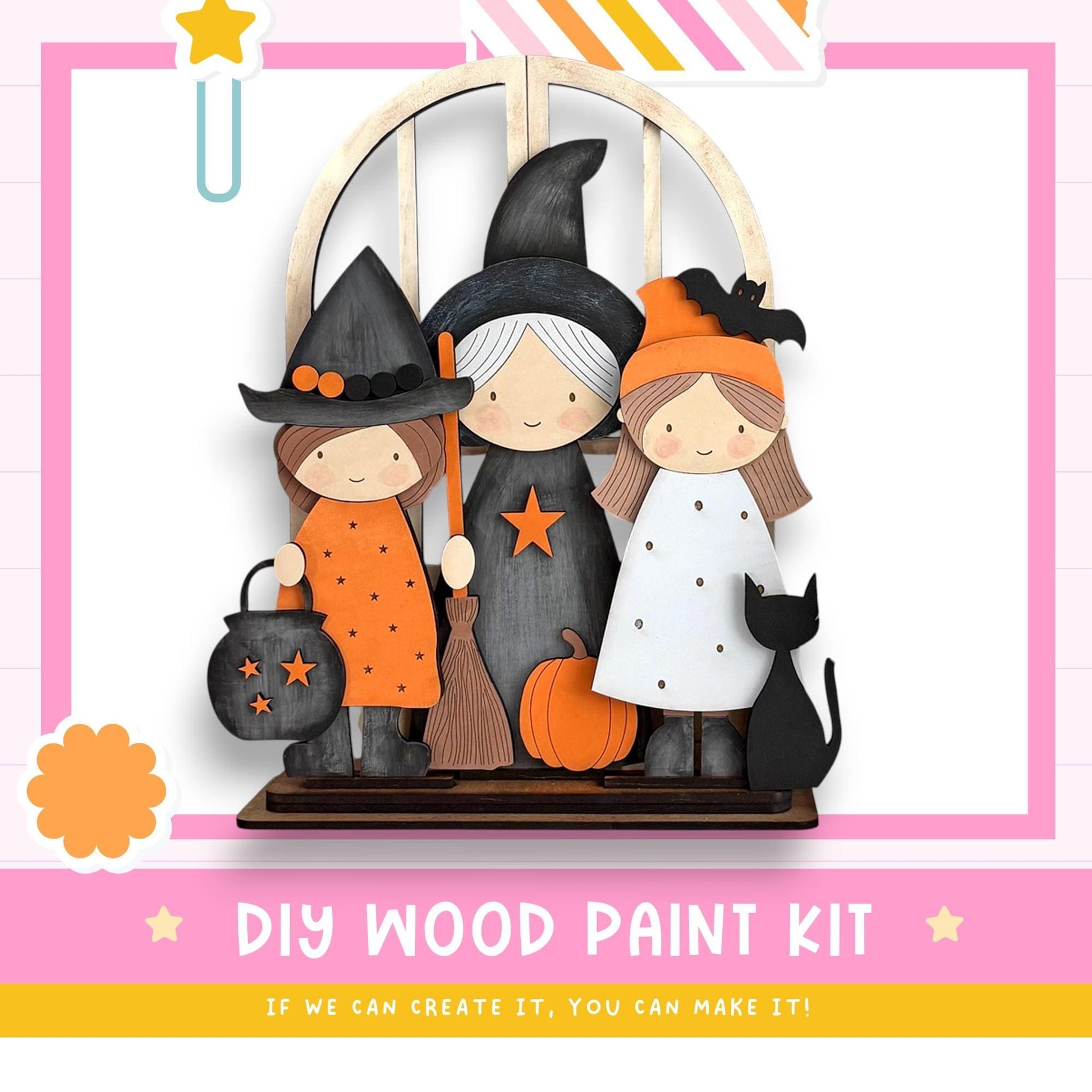 The image is a DIY wood paint kit featuring three wooden figures dressed in Halloween costumes, including a witch, a girl, and a cat, set against a pink and white background.