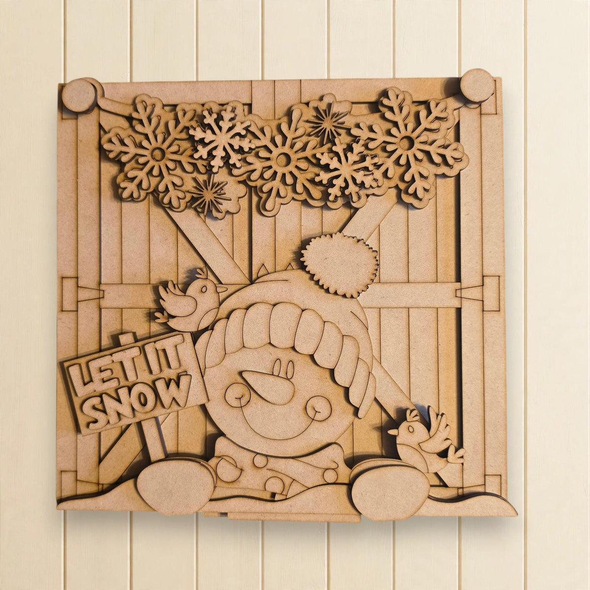 A wooden cutout of a snowman with a sign that says "LET IT SNOW" is displayed on a wall.
