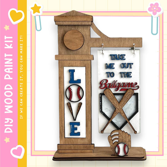 a wooden baseball-themed display with the word "LOVE" prominently displayed. The display includes a wooden baseball bat, a baseball glove, and a baseball, all set against a pink and yellow background.