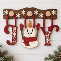 A wooden snowman decoration with a red scarf and a red hat, along with the word "Joy" made of wooden letters, is displayed on a wooden board.