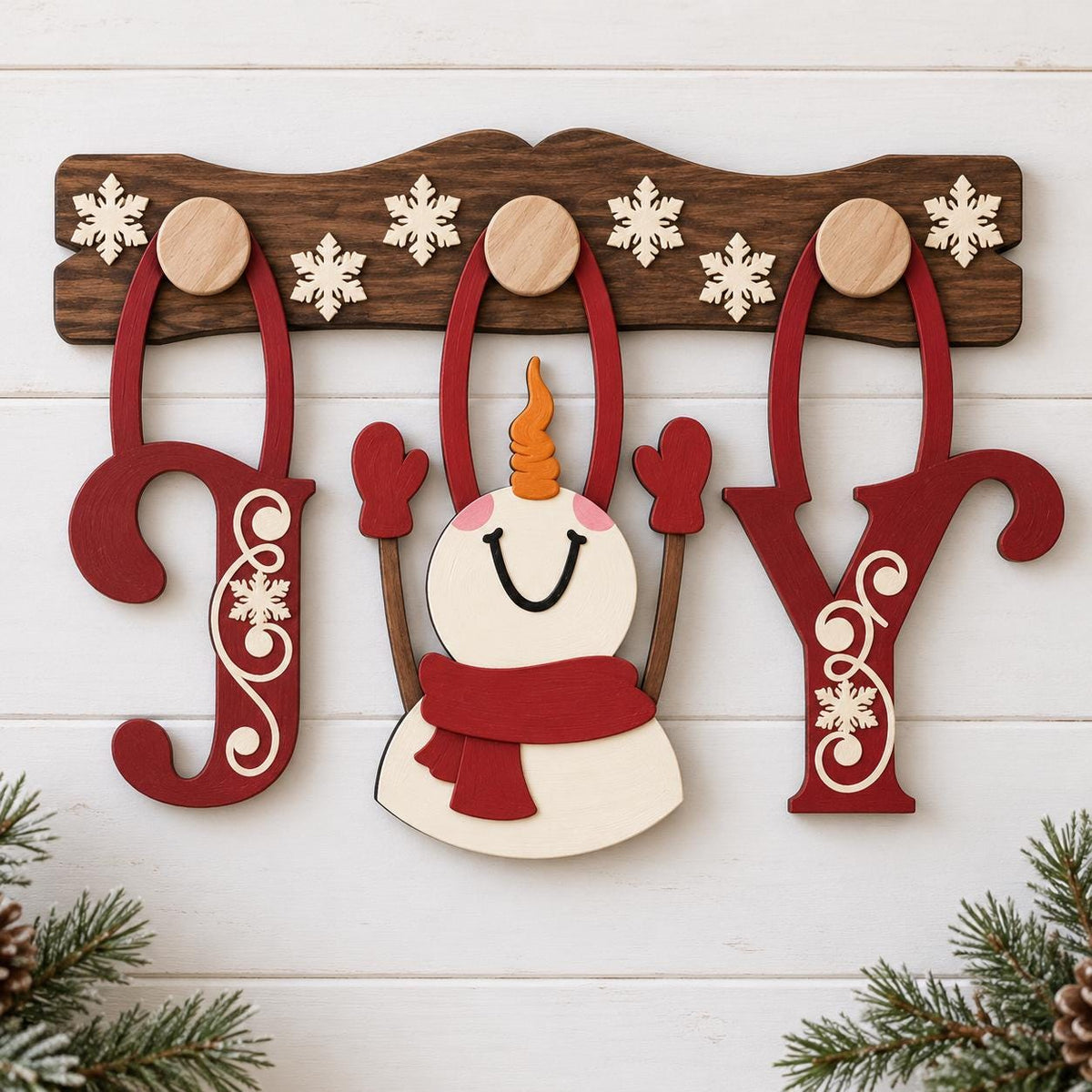 A wooden snowman decoration with a red scarf and a red hat, along with the word "Joy" made of wooden letters, is displayed on a wooden board.