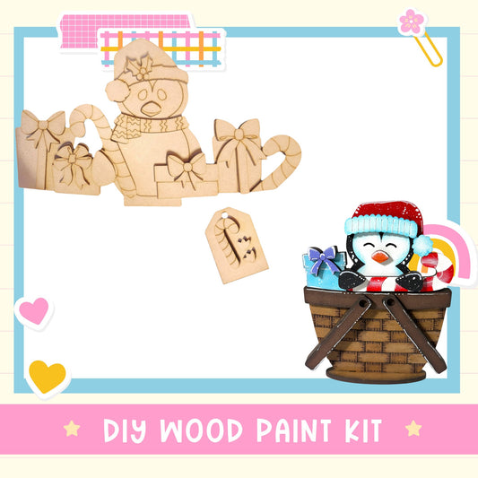The image is a DIY wood paint kit featuring a wooden penguin figure and a wooden basket with a penguin figure inside.