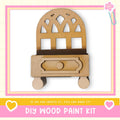 a DIY wood paint kit, with a wooden cabinet or shelf depicted in the center. The kit appears to be made of wood and has a drawer. The image is framed with a pink border and includes a heart symbol on the left side. The text "DIY WOOD PAINT KIT" is displayed at the bottom of the image.
