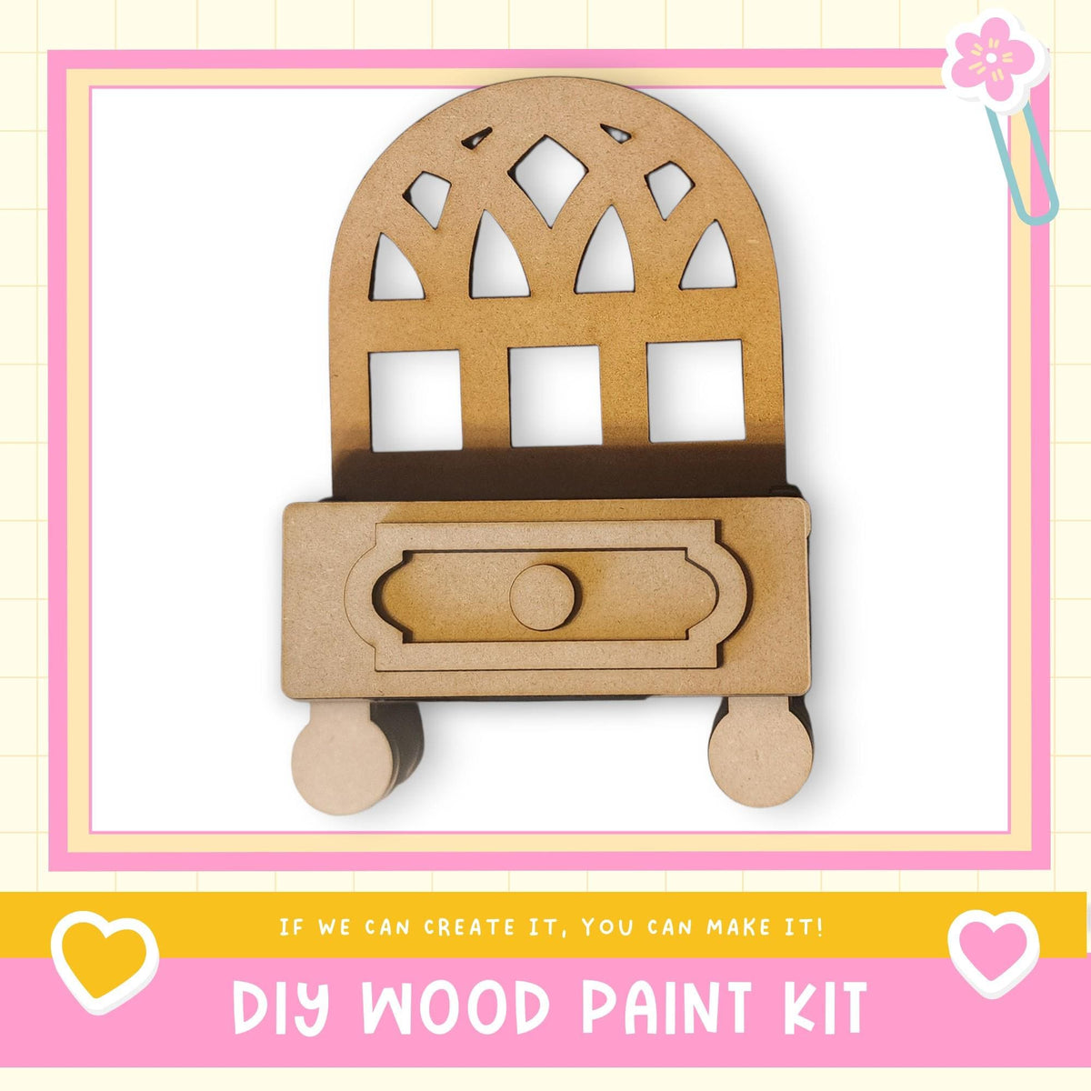 a DIY wood paint kit, with a wooden cabinet or shelf depicted in the center. The kit appears to be made of wood and has a drawer. The image is framed with a pink border and includes a heart symbol on the left side. The text "DIY WOOD PAINT KIT" is displayed at the bottom of the image.