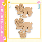 two wooden cutouts of rabbits, one holding a basket of carrots, set against a pink and yellow background with decorative elements.