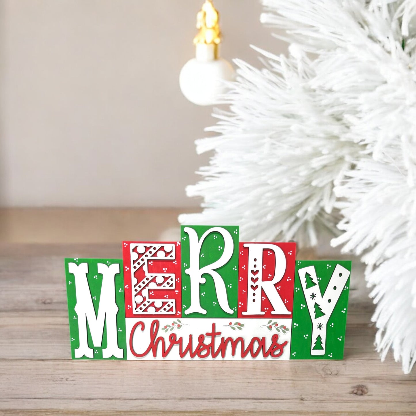 a wooden block that says merry christmas next to a christmas tree