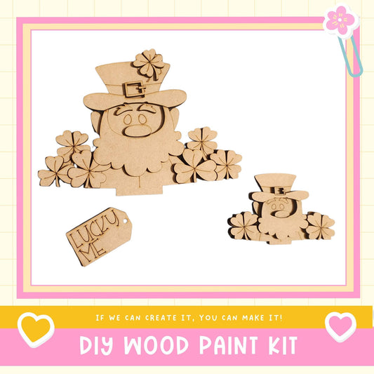 a DIY wood paint kit with a focus on creating a wooden cutout of a leprechaun. The kit includes a wooden cutout of a leprechaun, a tag with the word "Lucky Me", and a heart-shaped tag. The kit is presented in a pink and yellow frame, and the text encourages viewers to "If we can create it, you can make it!"