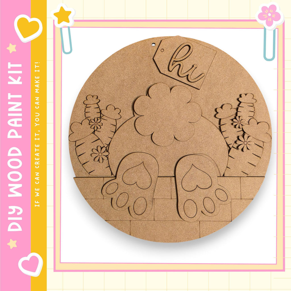 The image is a circular wooden craft kit featuring a design of a rabbit's feet and a flower.