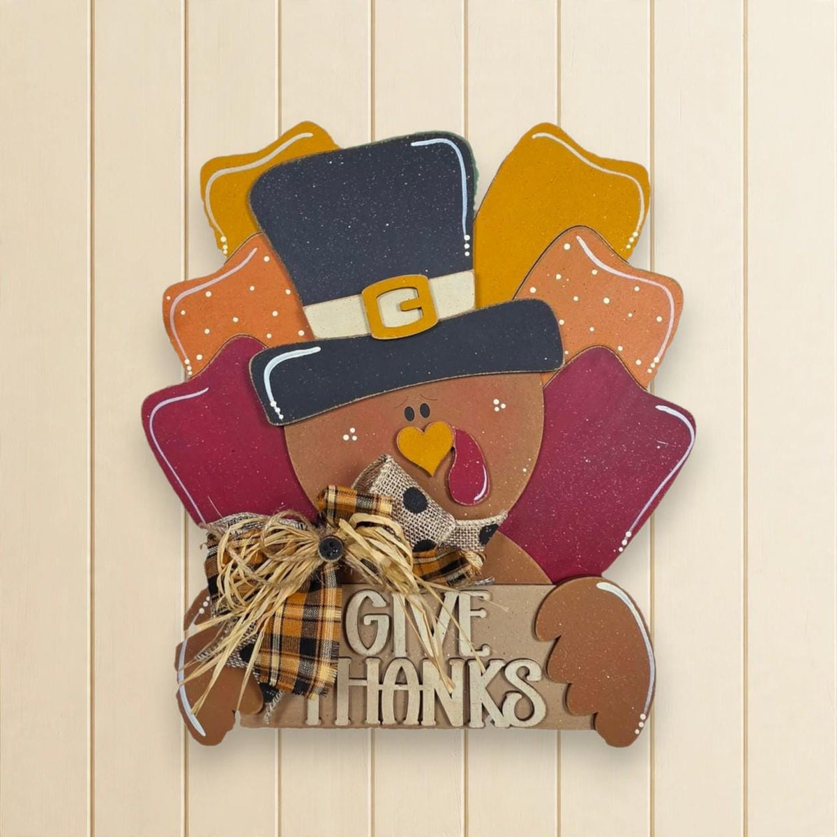 A wooden sign with a turkey wearing a top hat and holding a sign that says "Give Thanks".