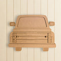 A cardboard cutout of a pickup truck is displayed against a white wooden background.