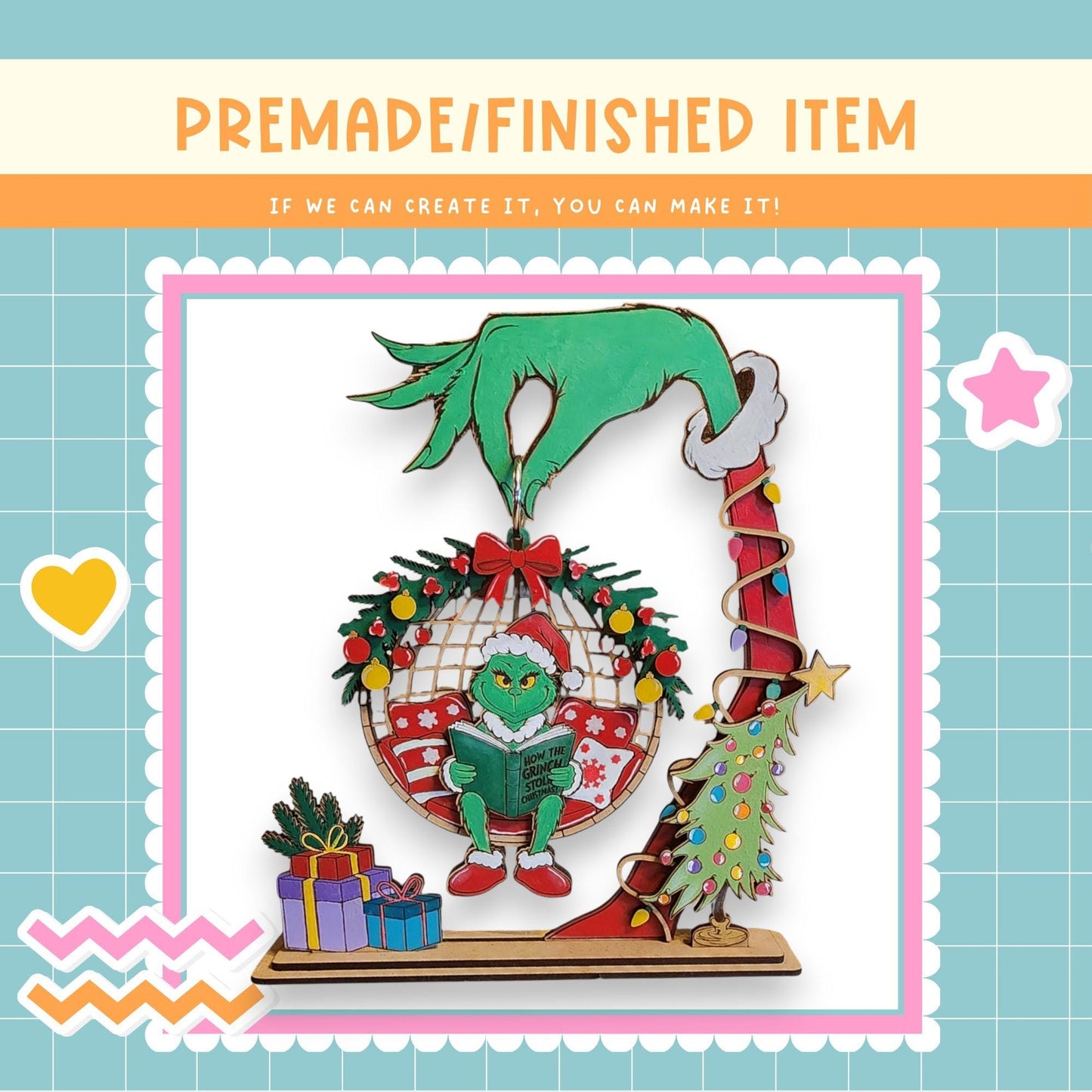 The image is a collage featuring a hand holding a Christmas ornament with a green frog wearing a Santa hat and reading a book. The ornament is surrounded by a wreath, presents, and a Christmas tree. The background is a light blue color with a grid pattern.