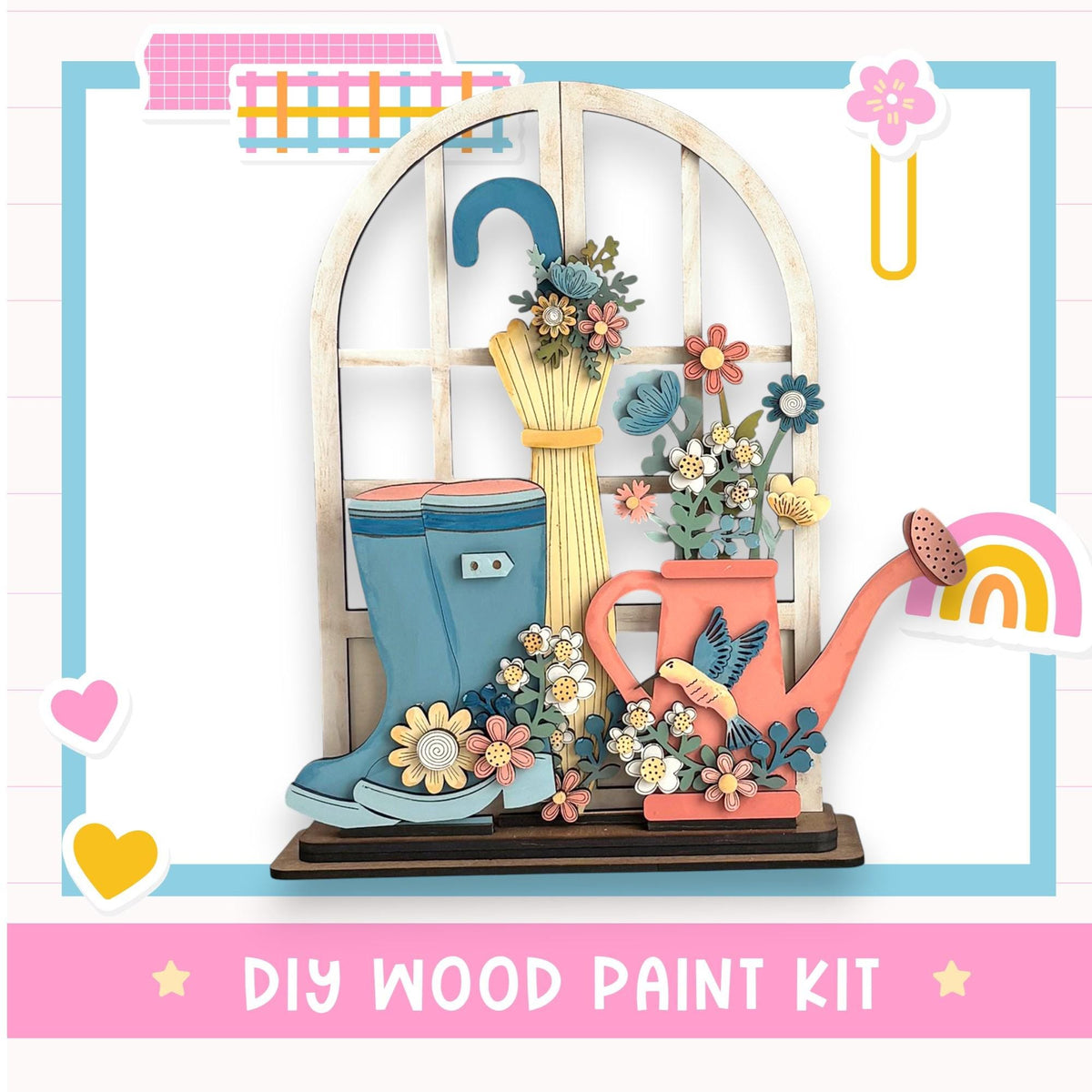 The image is a colorful and whimsical DIY wood paint kit featuring a wooden window with a flower arrangement, a pair of blue rain boots, and a pink watering can.