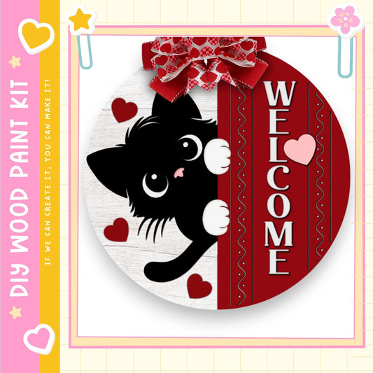 A black cat with white paws is peeking out from behind a red and white striped frame, with hearts and a bow around the frame.