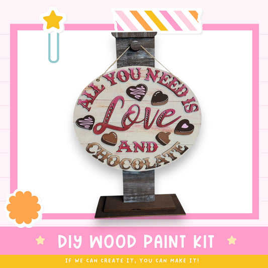 a DIY wood paint kit for creating a wooden sign with the message "All you need is love and chocolate".