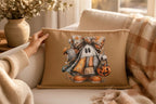 A hand is holding a pillow with a Halloween-themed design featuring a ghost character.