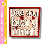 a wooden sign with the text "Love you beary much" in a red frame.