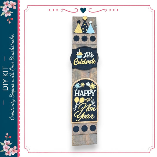 a wooden sign with various decorative elements, including a heart, a party hat, and a "Let's Celebrate" sign. The sign appears to be a DIY kit for creating a festive display.