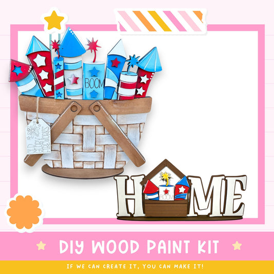 a DIY wood paint kit, with a basket filled with fireworks and a wooden sign that says "HOME". The kit appears to be made of wood and is designed for creating a wooden sign. The kit is presented in a pink and white color scheme, with the word "HOME" prominently displayed on the wooden sign.